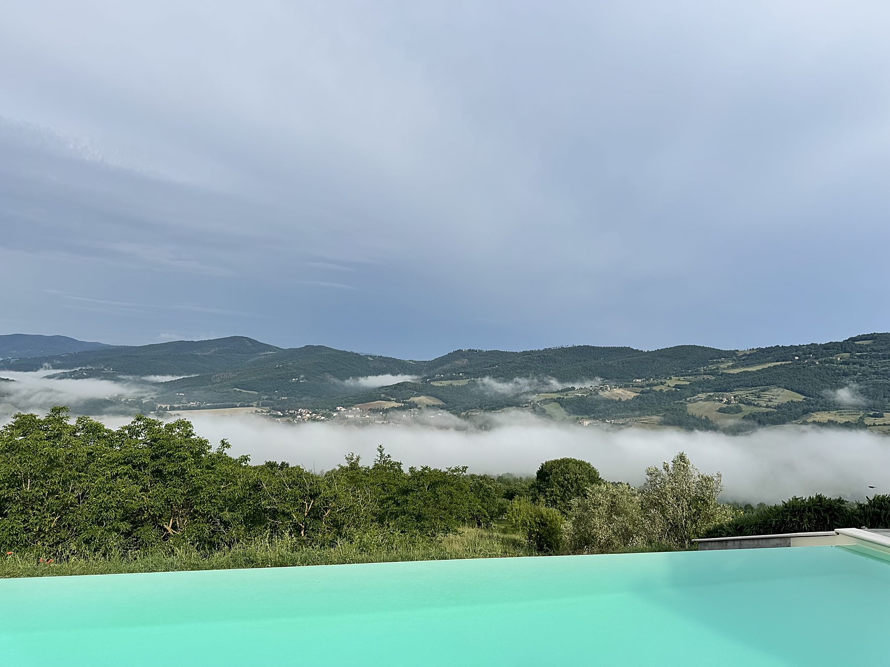 Infinity pool edge with morning mist over the Niccone Valley